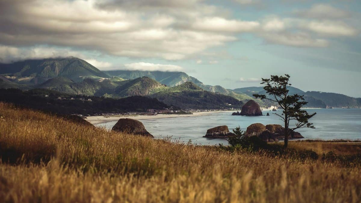 Beautiful view of Cannon Beach, Oregon, featuring Haystack Rock with coastal mountains in the background.