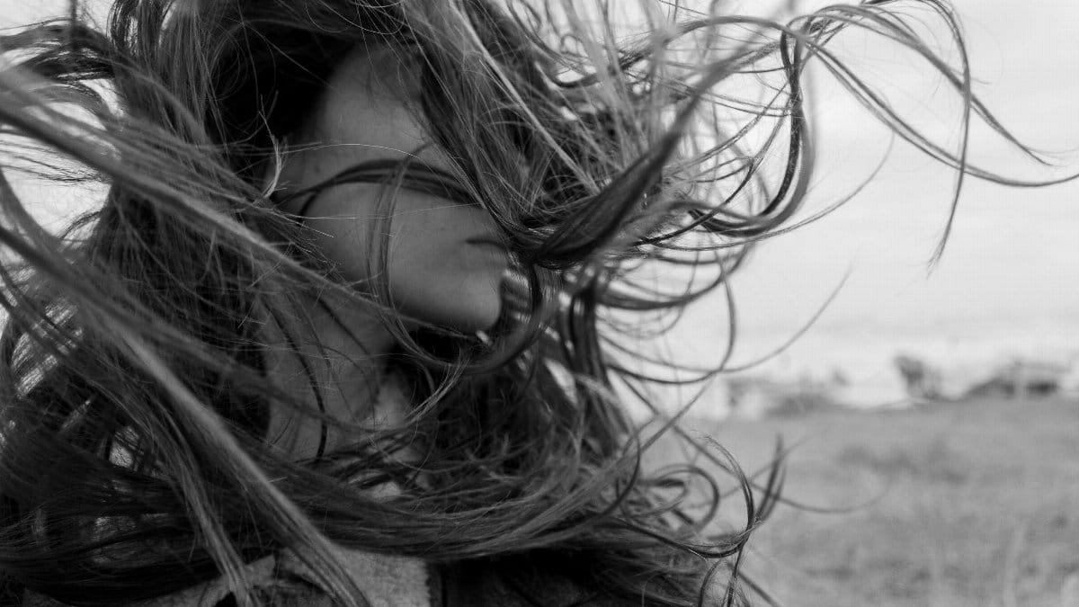 Black and white portrait of a woman with windblown hair creating dramatic movement.