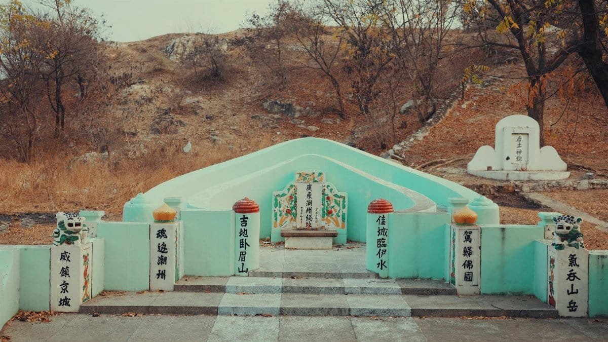 A traditional Chinese grave monument set against an autumn landscape, featuring intricate carvings and inscriptions.