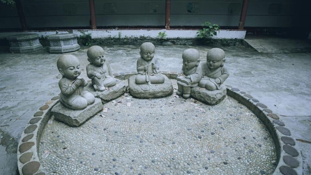 Five stone monk statues sit serenely in an outdoor courtyard, exuding tranquility and spiritual calm.