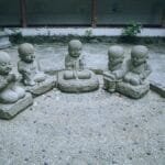 Five stone monk statues sit serenely in an outdoor courtyard, exuding tranquility and spiritual calm.