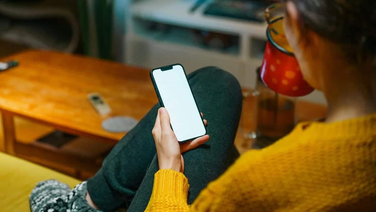 A person relaxing on a sofa with a smartphone, enjoying a warm winter evening indoors.