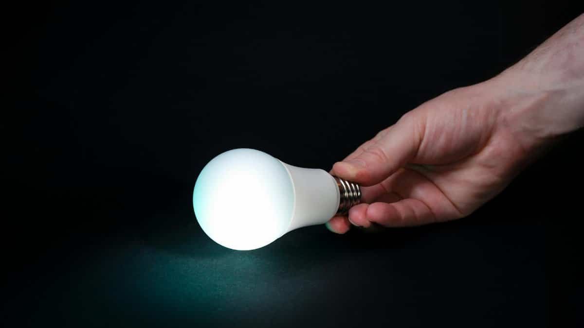 A glowing light bulb held by a hand against a dark background symbolizes innovation and ideas.