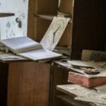 A cluttered, dusty office with open books, papers, and shelves, evoking a rustic and abandoned feel.