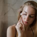 A woman using a jade roller on her face as part of her skincare routine.