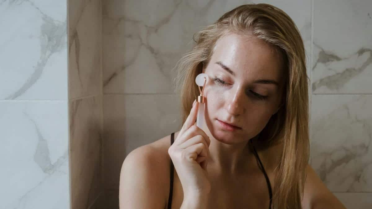 A woman using a jade roller on her face as part of her skincare routine.