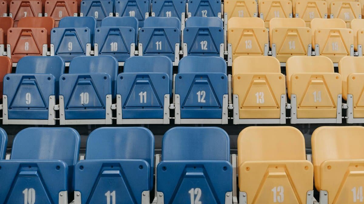 Uniform rows of red, blue, and yellow stadium seats with numbers visible.