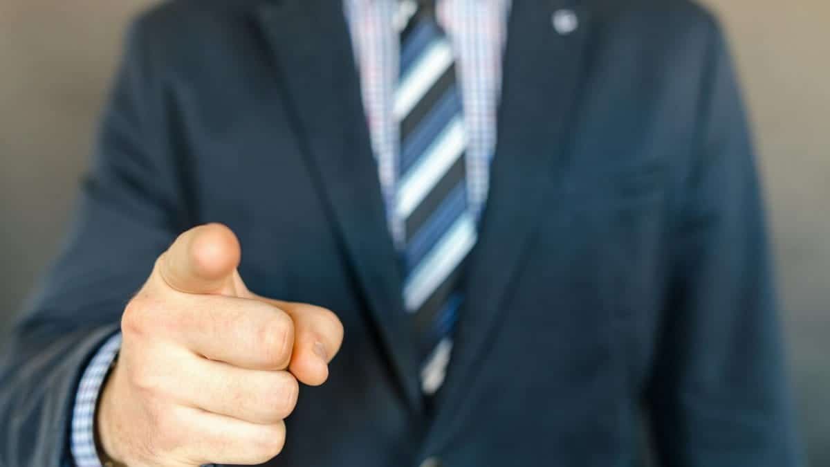 A businessman in a dark suit points forward, emphasizing focus and professionalism.