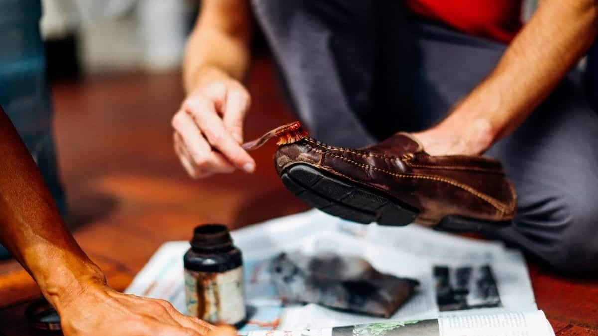 Close-up of hands skillfully polishing a leather shoe, showcasing craftsmanship and care.