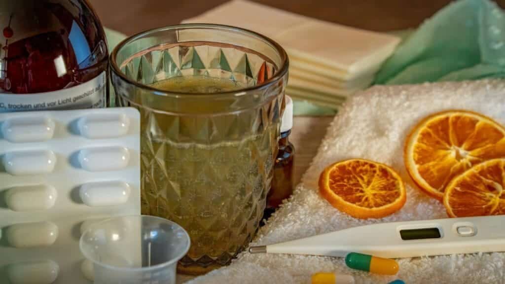 A collection of home remedies and medications for treating cold and flu symptoms, including a thermometer, pills, and herbal tea.