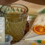 A collection of home remedies and medications for treating cold and flu symptoms, including a thermometer, pills, and herbal tea.