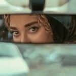 Close-up of woman's eyes in rearview mirror, conveying mystery and contemplation.