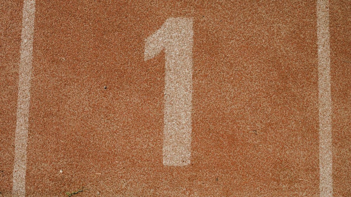 Close-up image of number one lane on a running track, symbolizing first place.