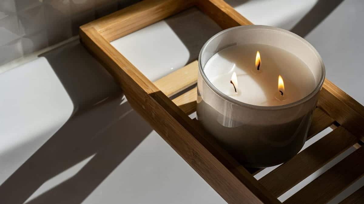 A minimalist setting with a lit candle on a wooden tray, casting warm shadows and creating a soothing ambiance.