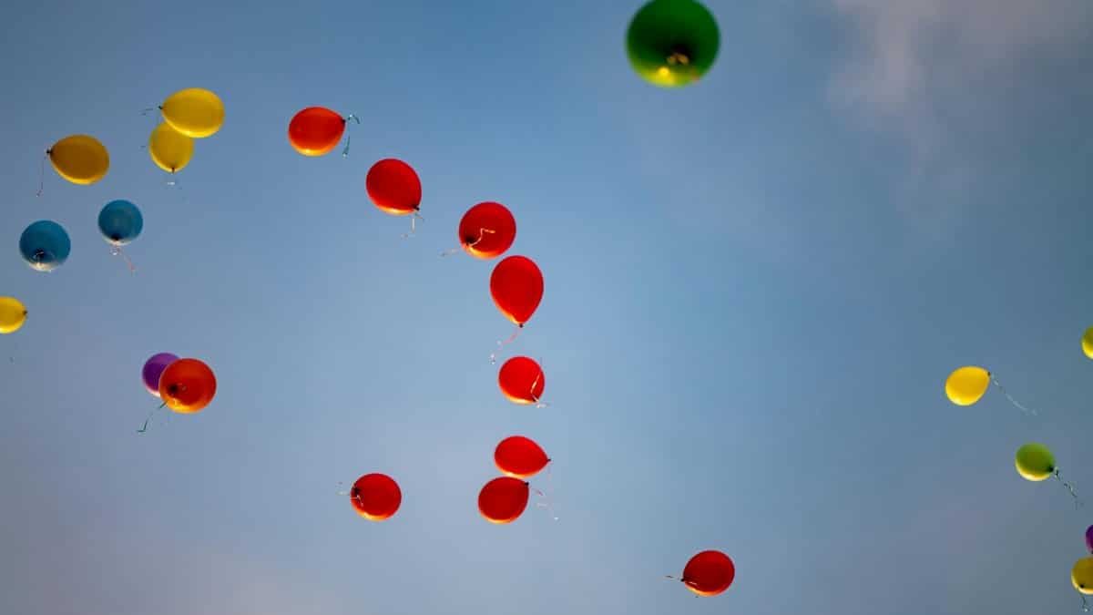 Vibrant balloons ascending against a clear blue sky, symbolizing celebration and joy.