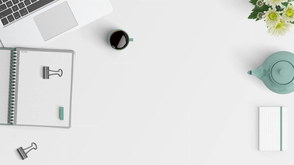 Clean minimalist workspace with a laptop, coffee, flowers, and stationery.