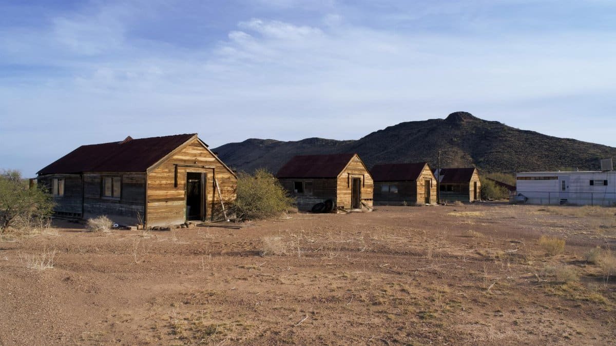 Historic wooden structures in an abandoned Arizona ghost town set against a desert backdrop.
