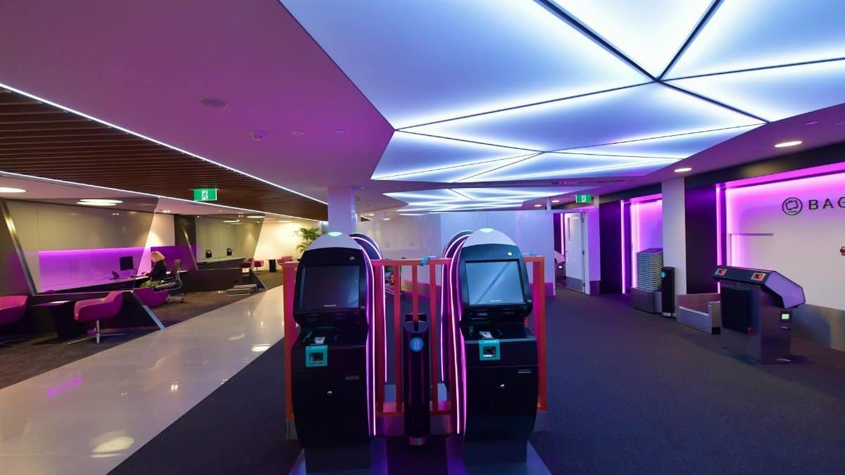 Stylish airport lounge featuring automated check-in machines and vibrant lighting.