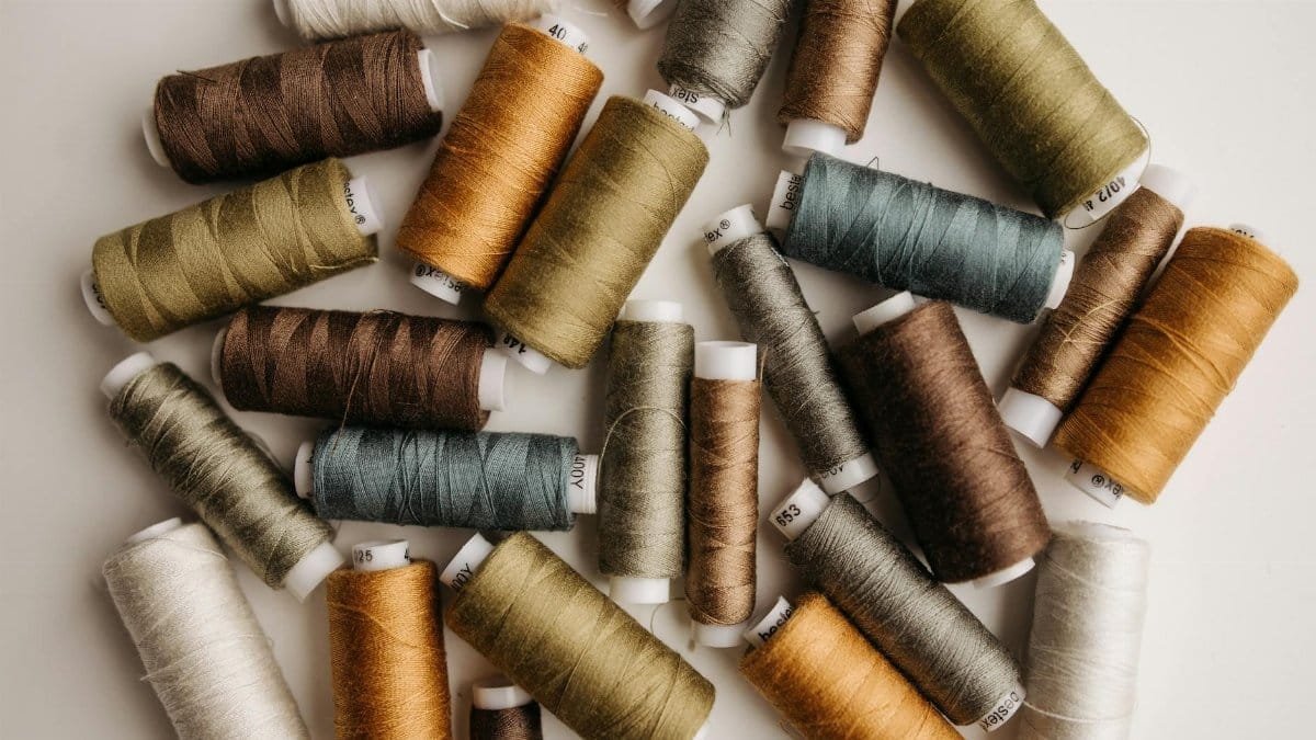 A collection of multicolored sewing threads arranged on a white surface, perfect for textile or crafting projects.