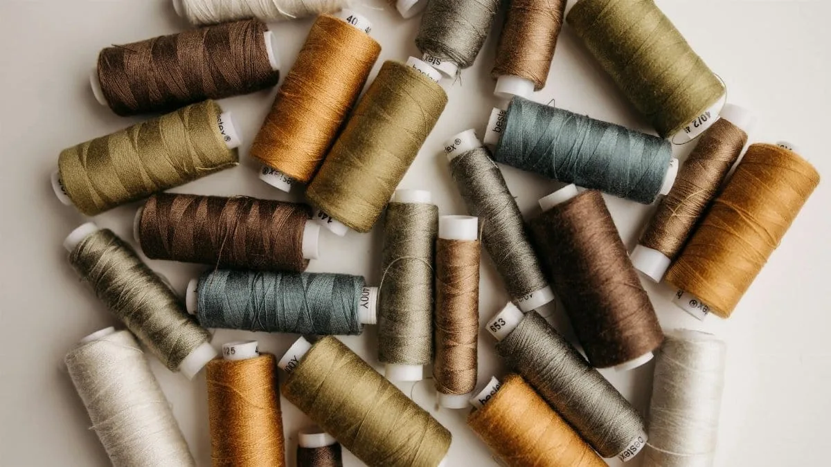 A collection of multicolored sewing threads arranged on a white surface, perfect for textile or crafting projects.
