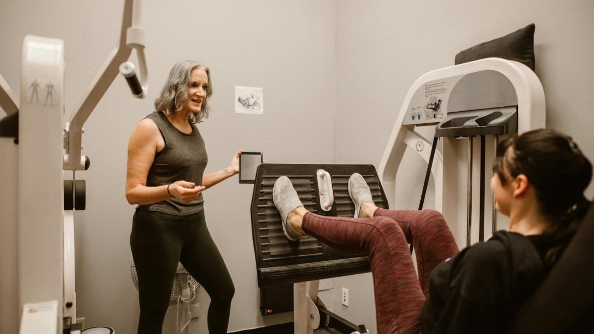 Two women exercising indoors, focusing on health and wellness at a gym.