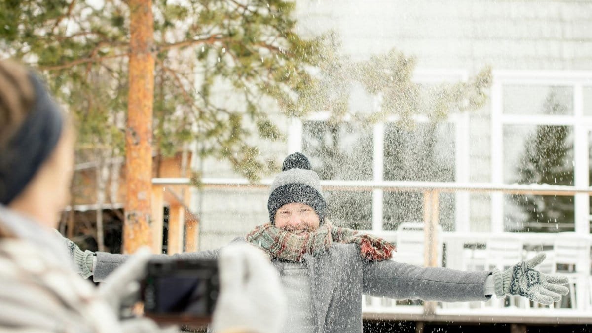 Man enjoying a playful snow day, arms wide open, capturing happy winter moment.