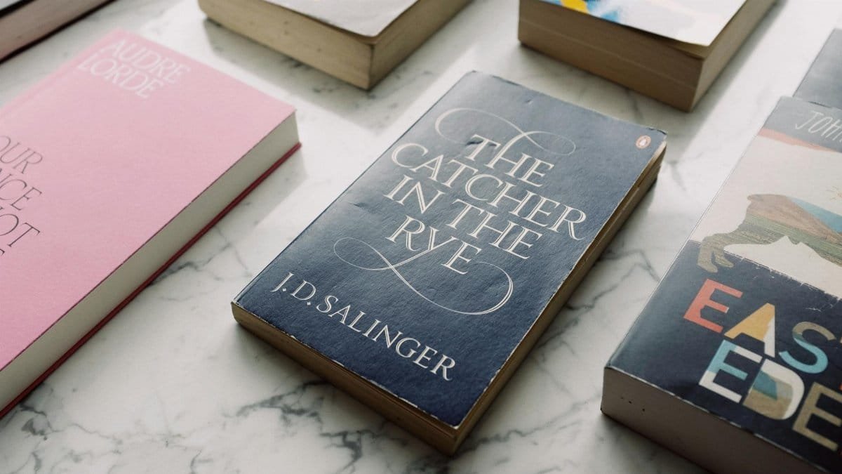 A collection of classic novels displayed on a marble surface, showcasing titles like 'The Catcher in the Rye.'