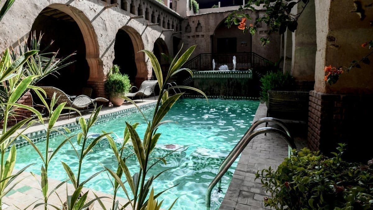 Stunning mediterranean-style poolside with stone arches and vibrant greenery. Perfect tropical retreat.