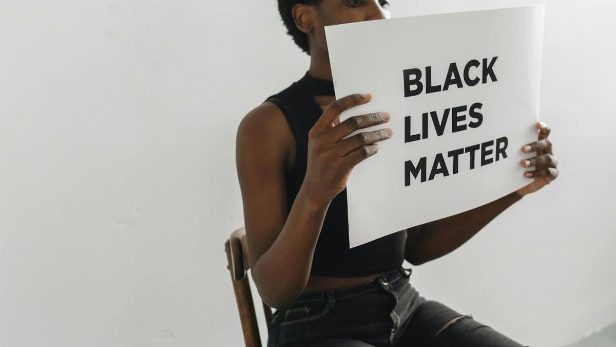 A woman holds a Black Lives Matter poster, highlighting racial equality and activism.
