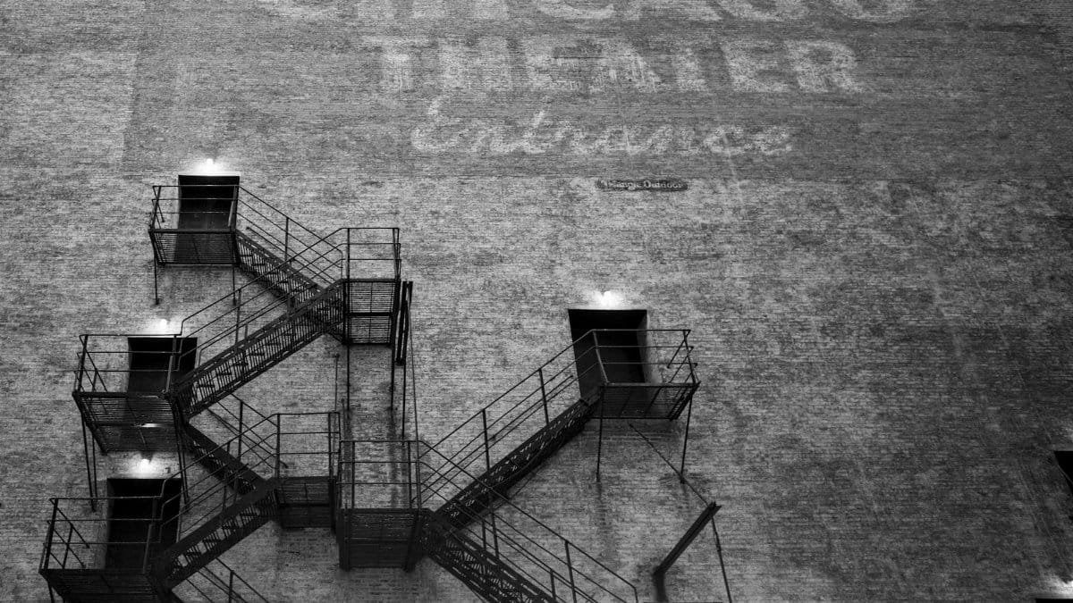 Monochrome image of a fire escape on a brick wall with Chicago Theater text.