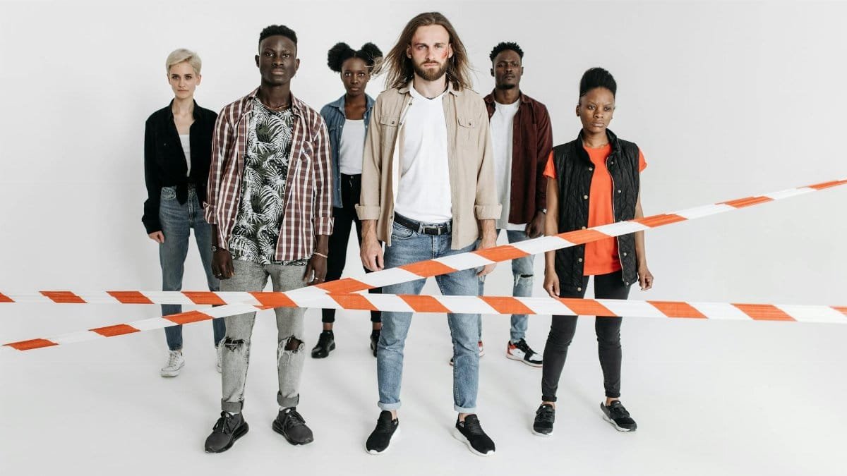 A diverse group of serious individuals lined up behind caution tape against a white background.