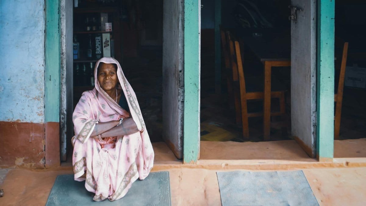 An elderly woman in traditional attire sitting peacefully in a doorway, capturing a moment of tranquility.