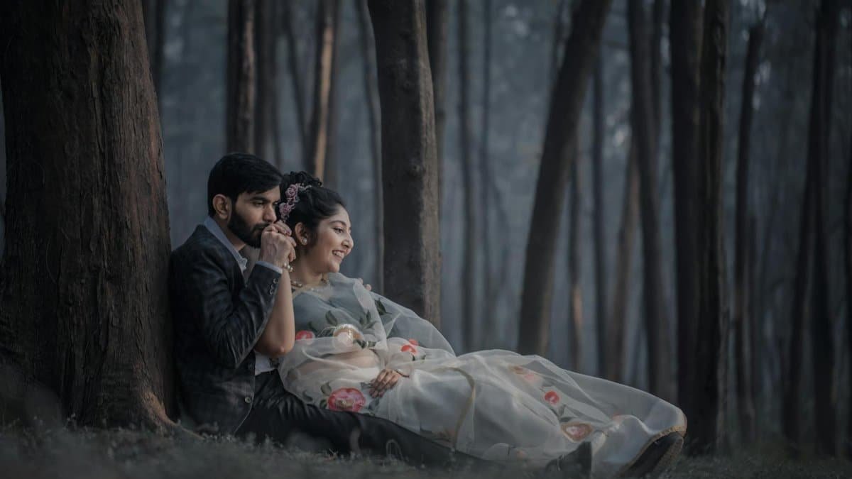 A loving couple sitting and embracing in a serene forest, capturing a romantic moment.