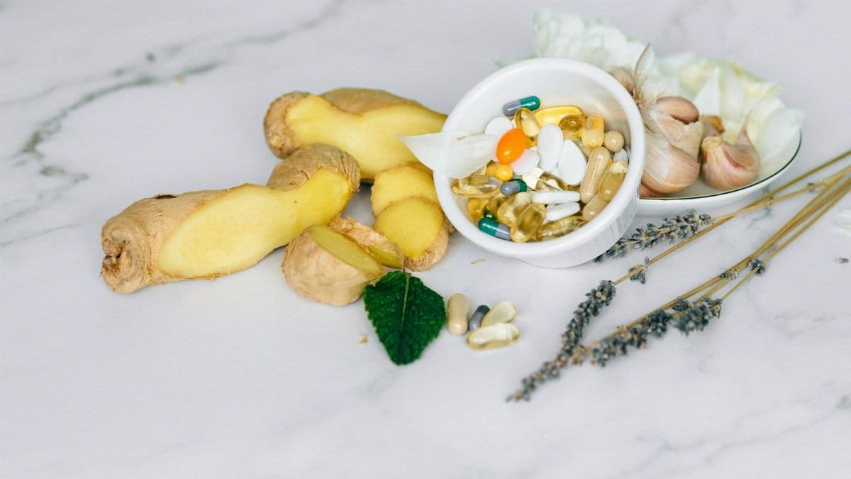 A flat lay featuring ginger, garlic, and various herbal supplements on a marble surface.