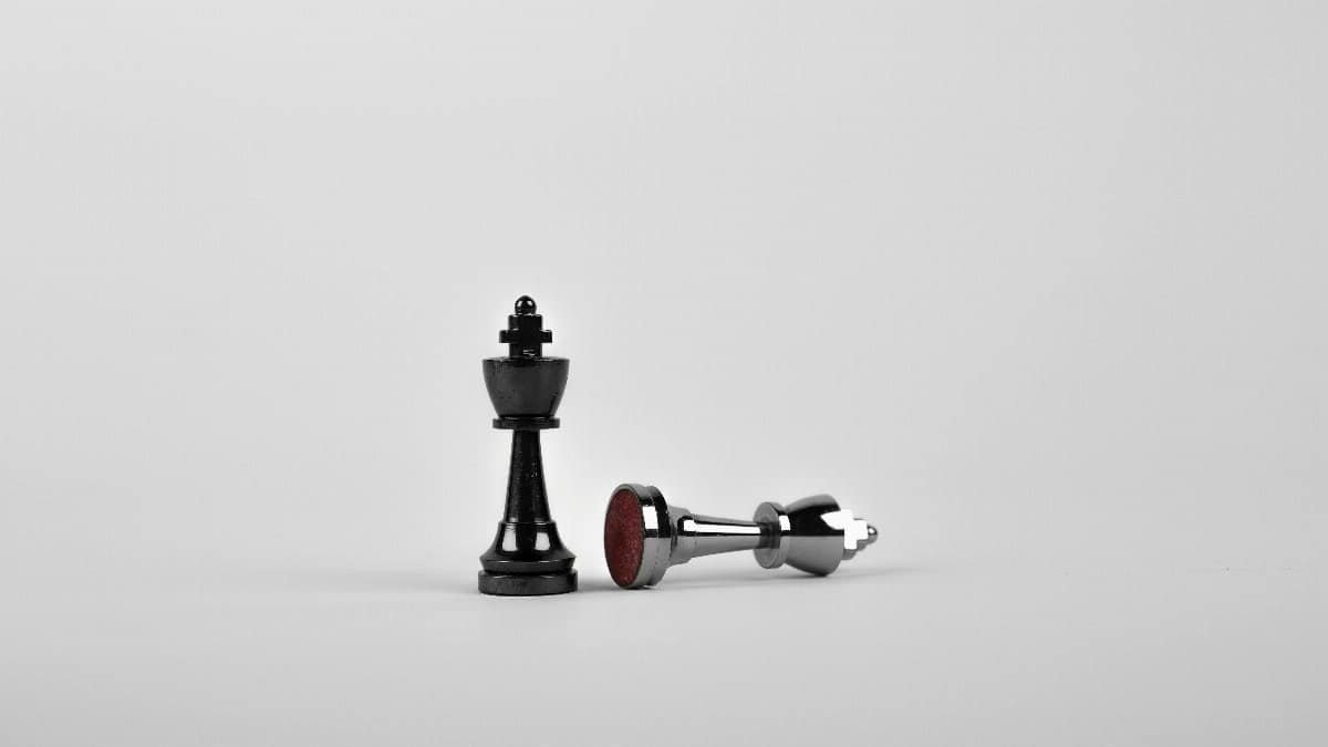 Close-up of chess king piece standing with a fallen piece symbolizing strategy and victory.