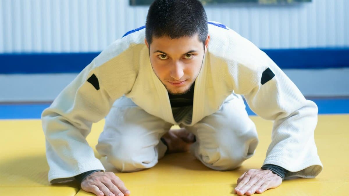 A male judoka bowing on a tatami mat during a judo training session, showing respect and focus.