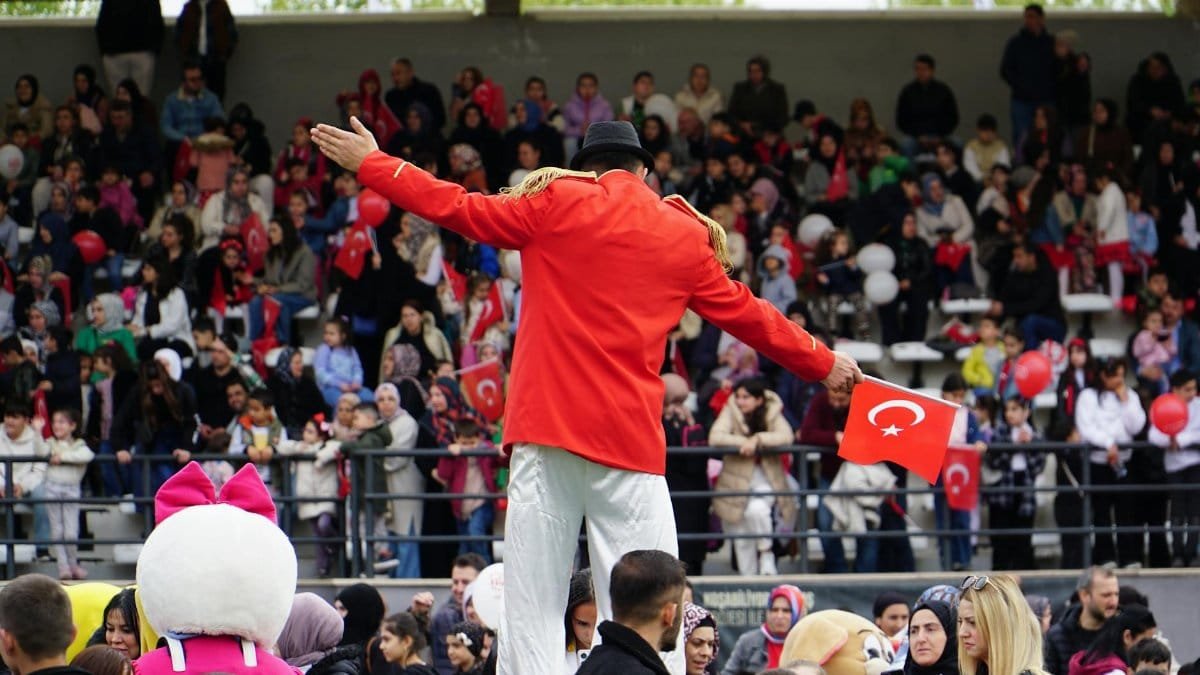 Lively event in İstanbul with a performer and Turkish flags, capturing joyous community spirit outdoors.