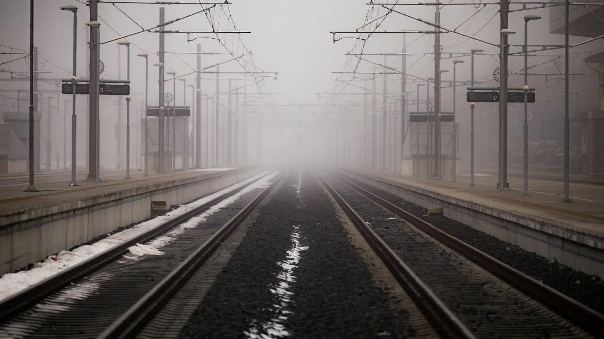 Misty railway platform enveloped in fog at a winter station.