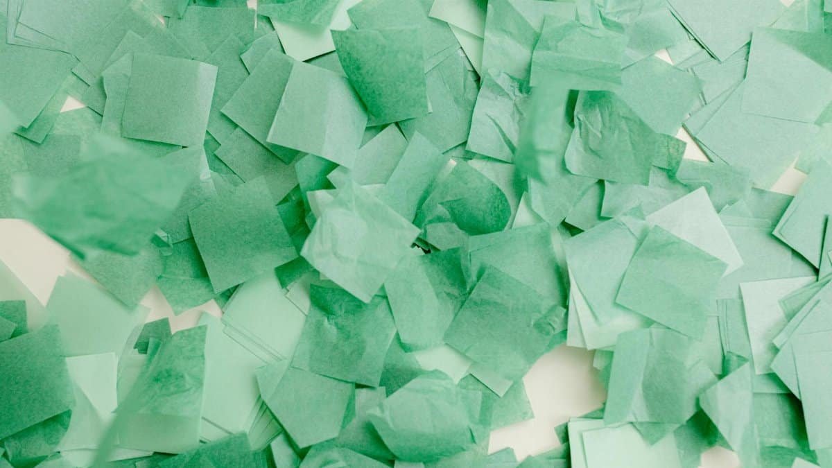 Abstract composition of overlapping green paper squares creating a vibrant textured pattern.