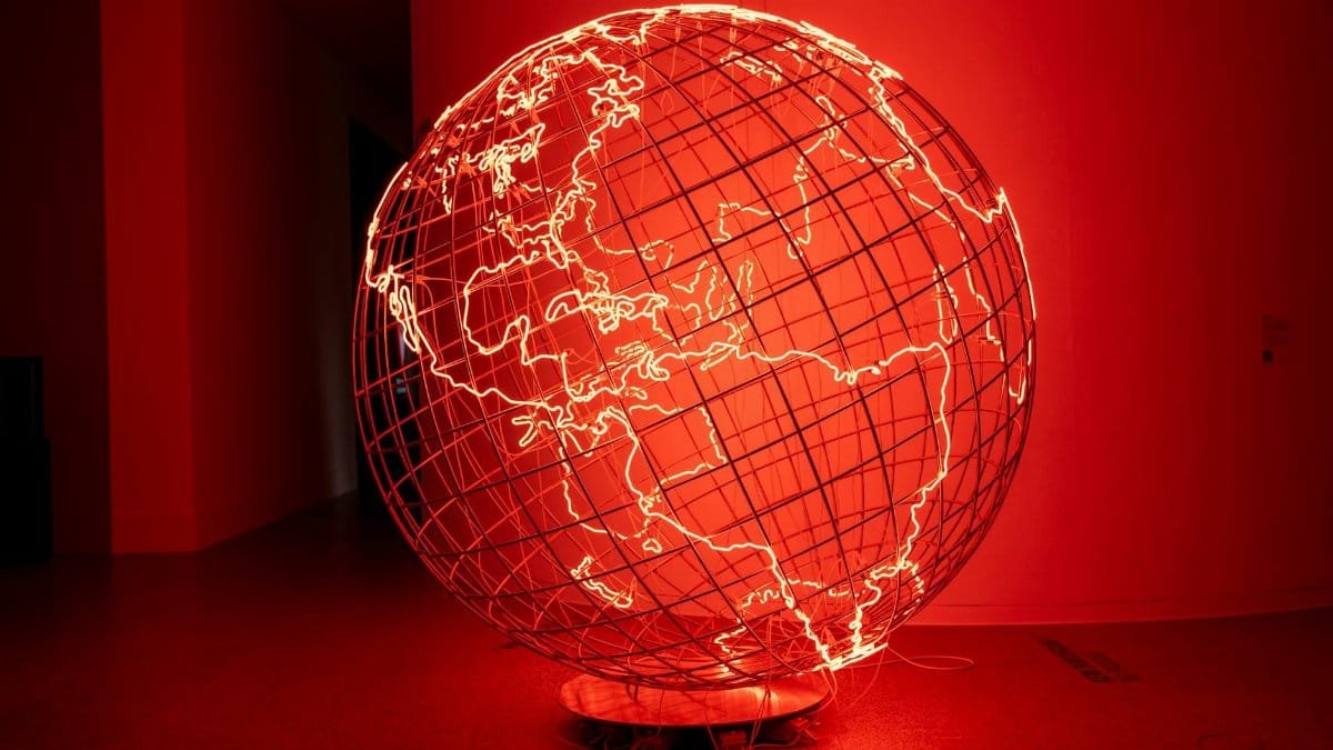 A striking illuminated globe sculpture displayed in a dimly lit art exhibition in Bonn, Germany.