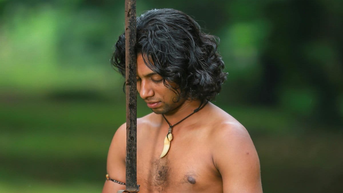 Shirtless man holding sword outdoors, embodying warrior spirit and cultural tradition.