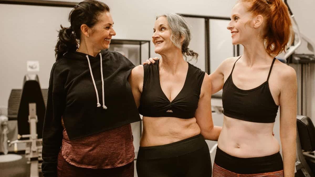Three women enjoying fitness and friendship in a gym, embracing healthy living.
