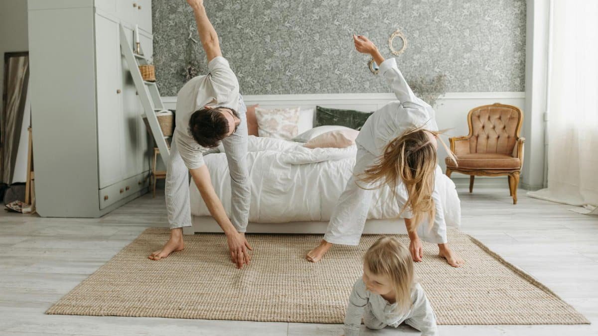 A family stretches together in a cozy bedroom, enjoying morning activities.