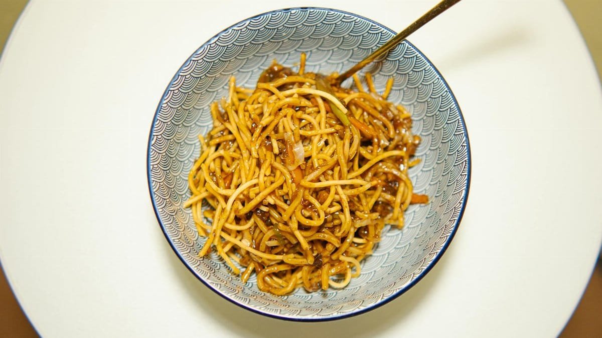 Appetizing Chinese noodles served in a decorative bowl with chopsticks on a table.