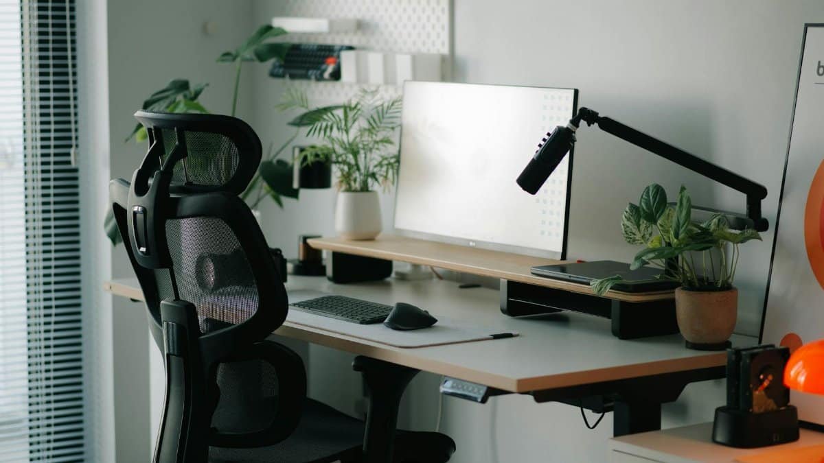 Stylish home office setup with ergonomic chair, plants, and modern desk accessories.