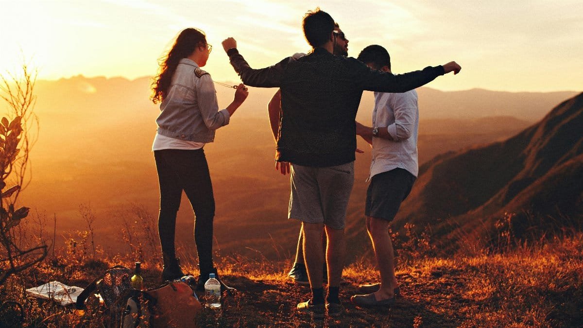 Joyful group of young adults enjoying a sunset view in a mountainous landscape in Brazil.