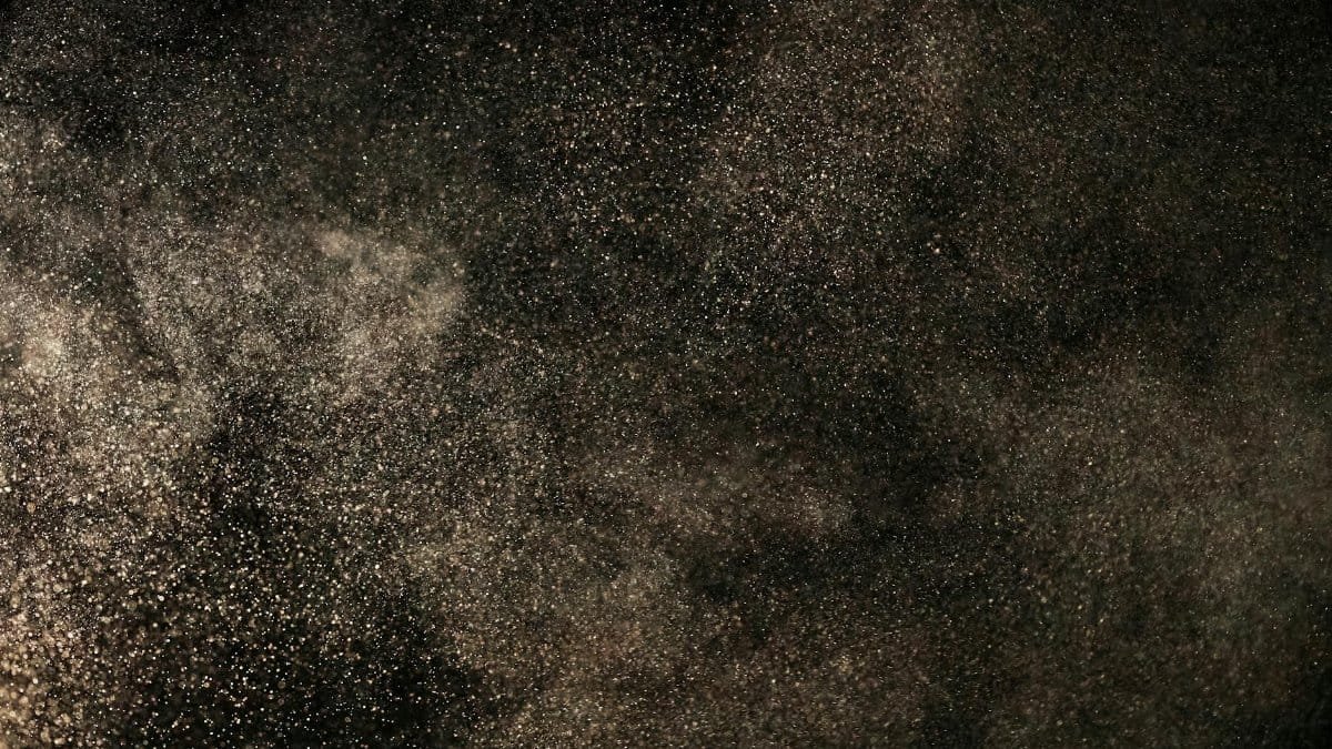 A captivating view of dust particles floating against a dark backdrop, creating a celestial feel.