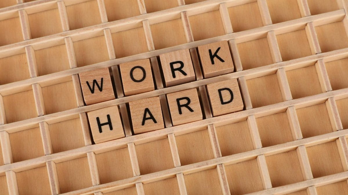 Creative wooden letter tiles forming the phrase 'work hard' on a grid. Perfect for motivation themes.