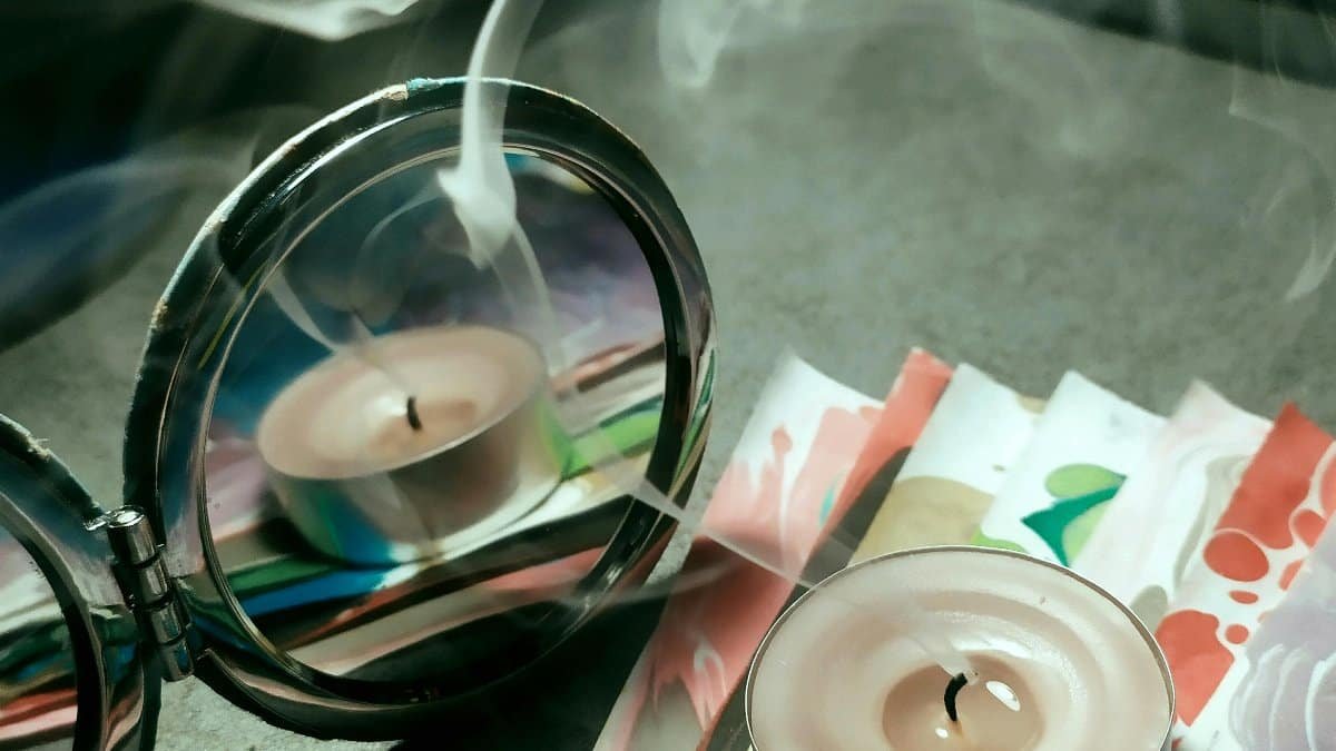 Aromatic candle with gentle smoke reflecting in a mirror creating a soothing ambiance.