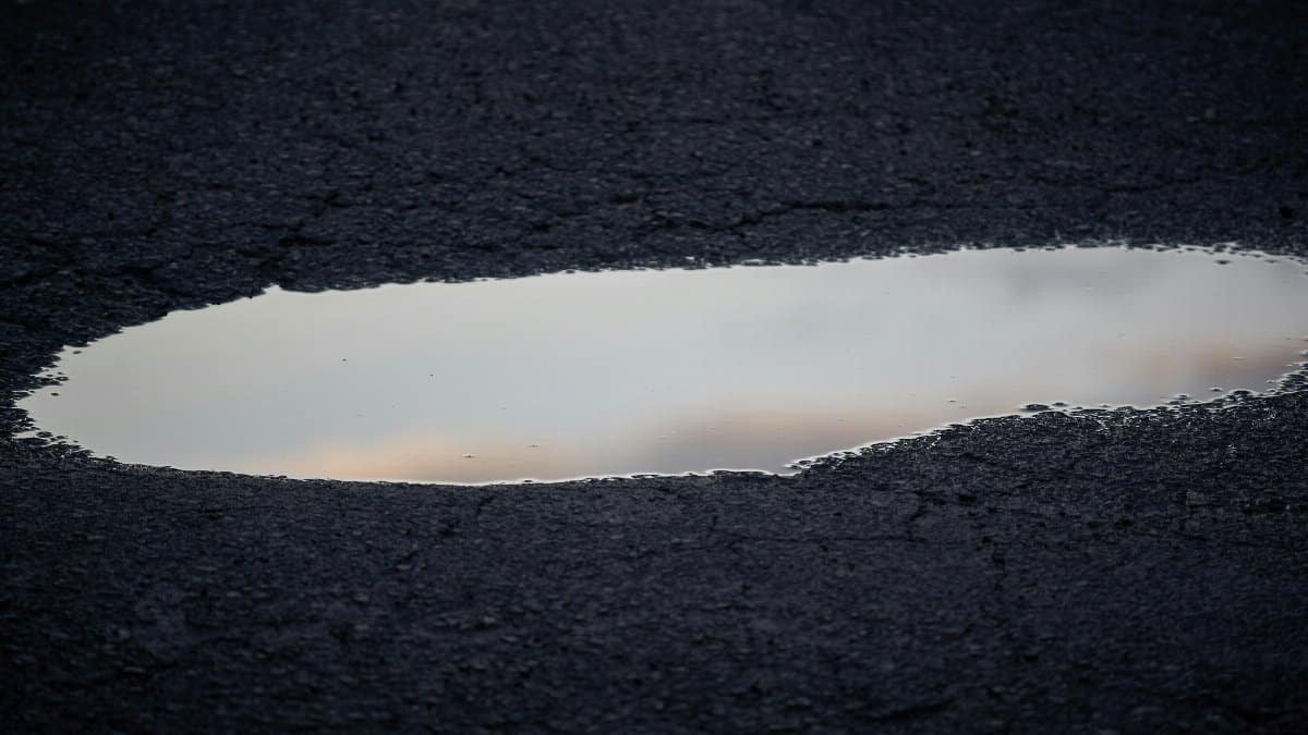 A close-up view of a reflective puddle on rough asphalt, capturing the tranquil ambience.